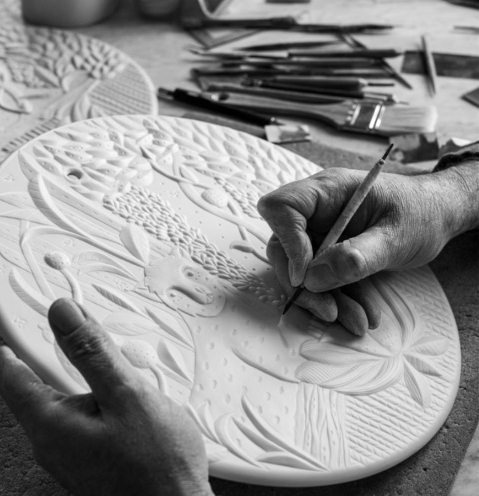 Artesano trabajando sobre una pieza de porcelana